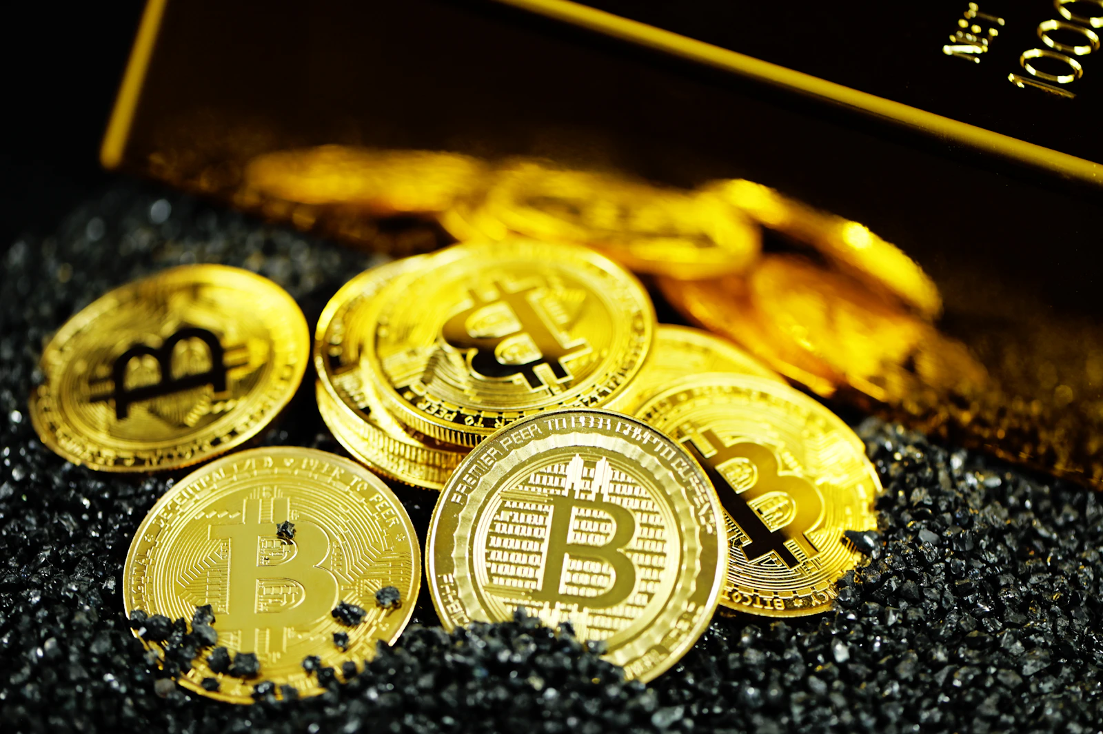 Žetony se symbolem bitcoinu vedle zlatého slitku.